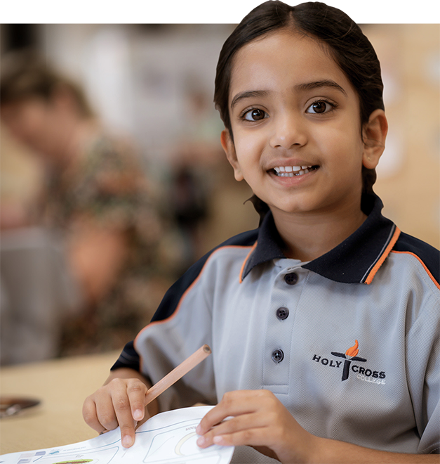 Young female student completing a worksheet in class, smiling at the camera.