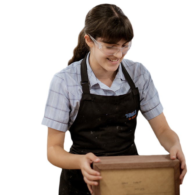 Female student putting together a wooden box. She is wearing safety goggles and an apron.